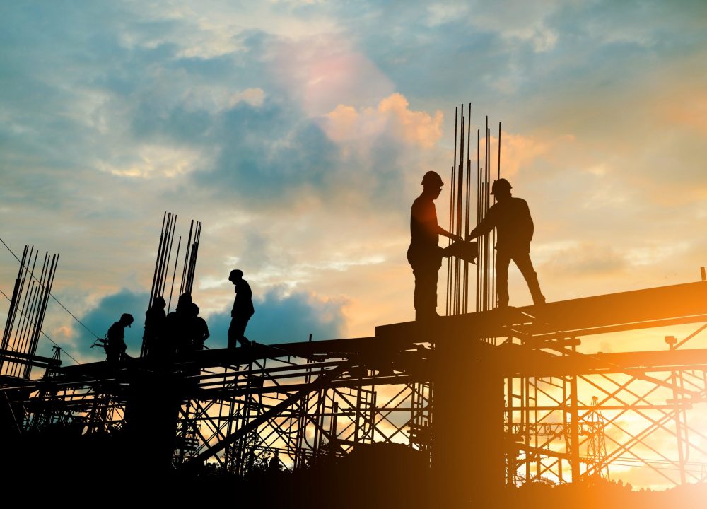 Silhouette of engineer and construction team working at site over blurred background sunset pastel for industry background with Light fair.